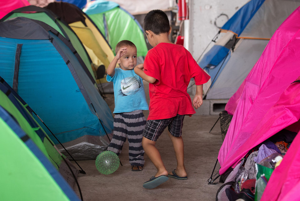 Migrant children playing among tents at Tijuana border