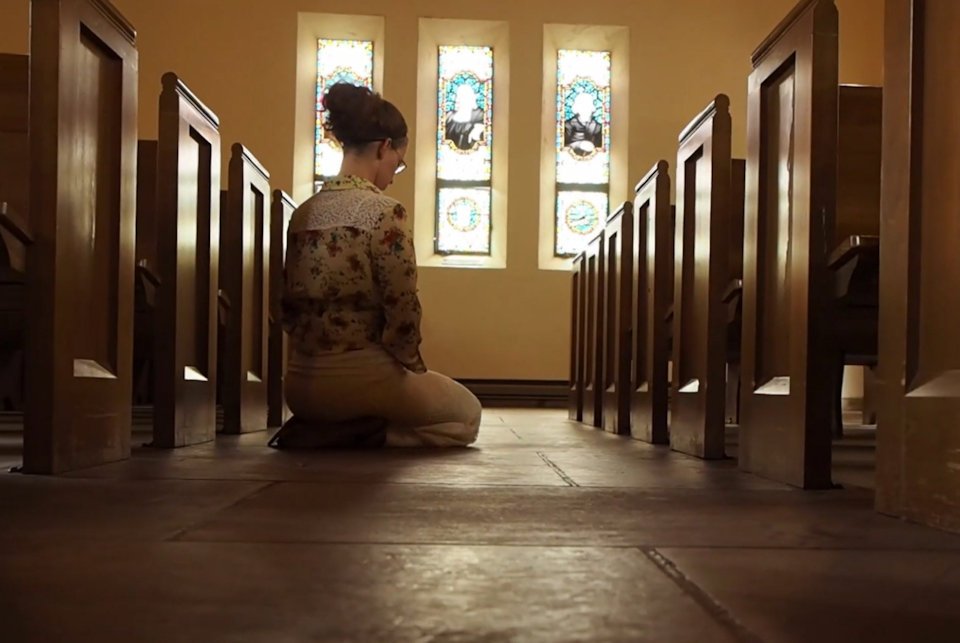 Woman kneeling in a church sanctuary