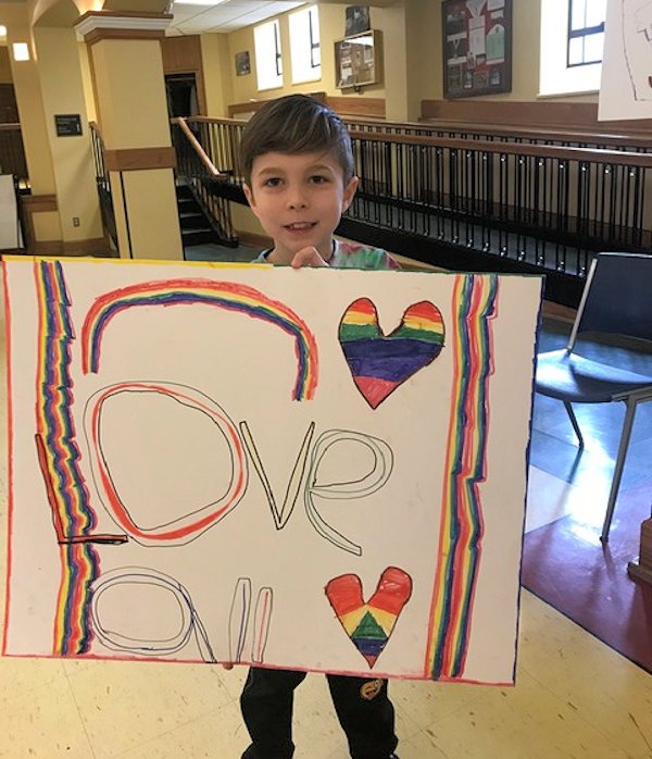 Young boy holds up welcome poster.