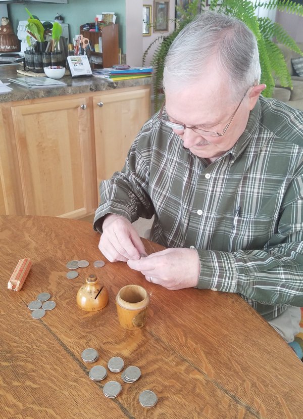 Man counting coins out of small wooden bank.