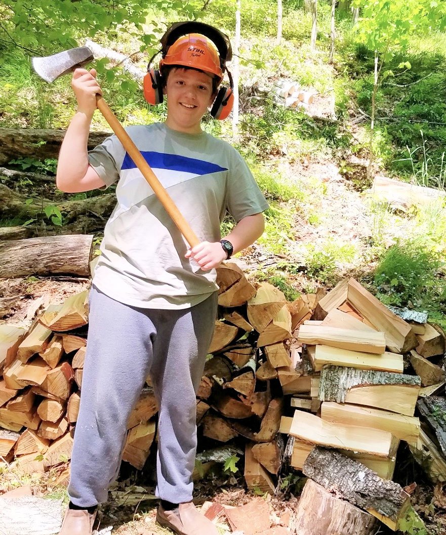 Nephew learns to swing an ax and split a log on the farm.