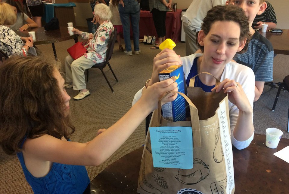 Mother and child put food in a bag.