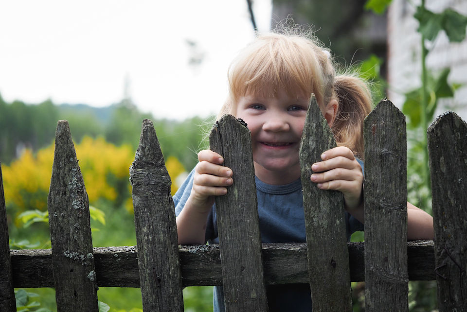 Girl peeking through picket fences