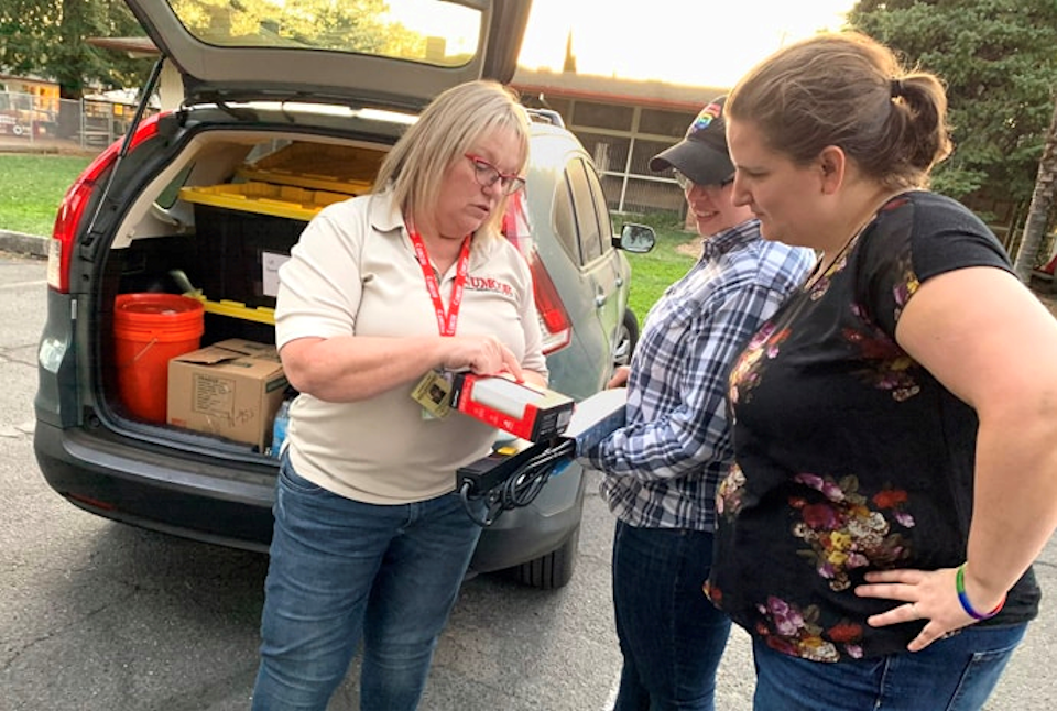 California-Nevada Conference Disaster Response Coordinator Sonja Edd-Bennett (left) shows Revs. Jacey and Emily Pickens-Jones (right), pastors of Sonoma United Methodist Church, features of USB chargers from the conference being donated to the church's hospitality enter.