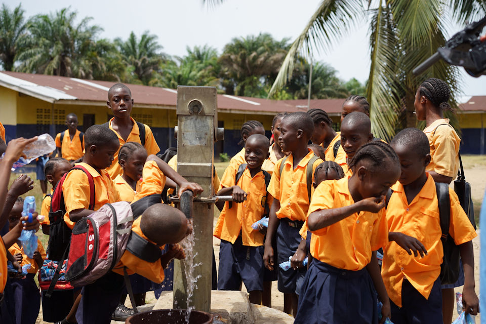 Children in Liberia gather around pump