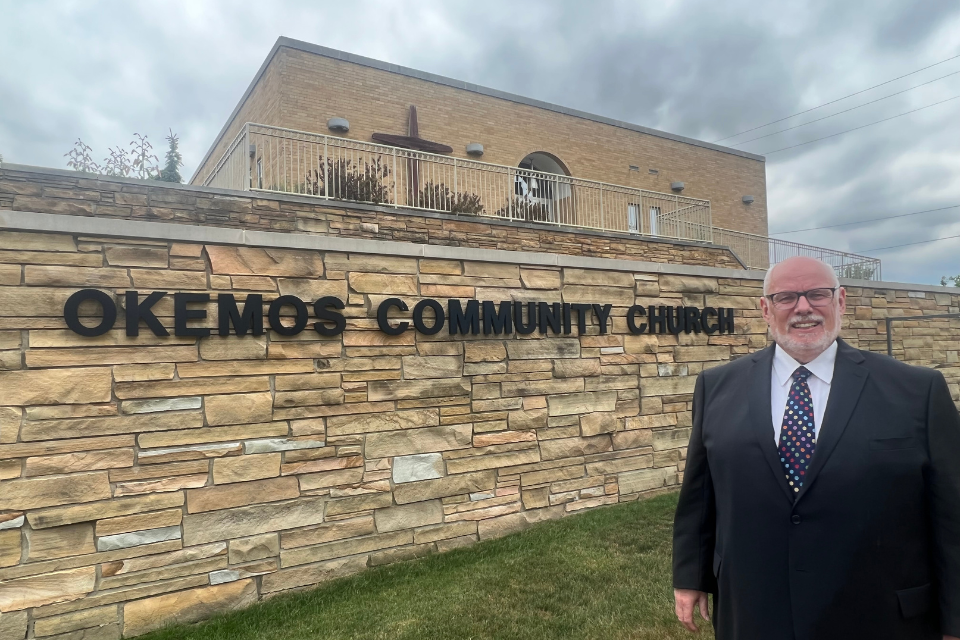 Rev. Rick Blunt in front of Okemos Community Church.