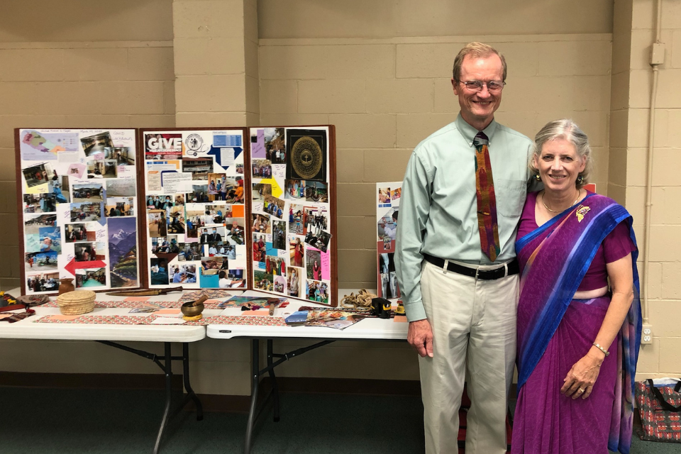 Les and Debbie Dornon standing next to their missionary display boards at a Michigan church.