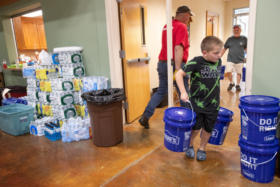 Boy carries flood bucket.