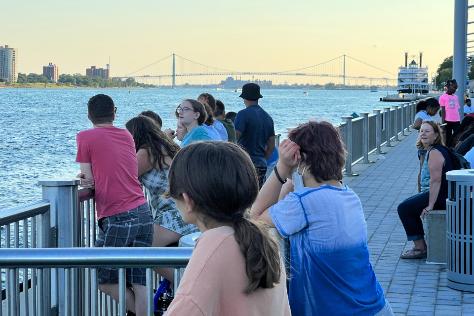 People standing along the riverfront in Detroit.