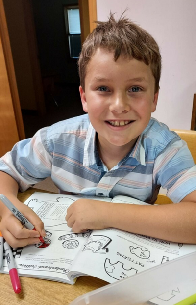 Boy coloring in coloring book