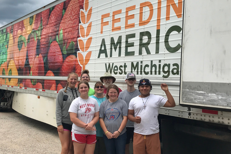 Volunteers standing next to food giveaway truck