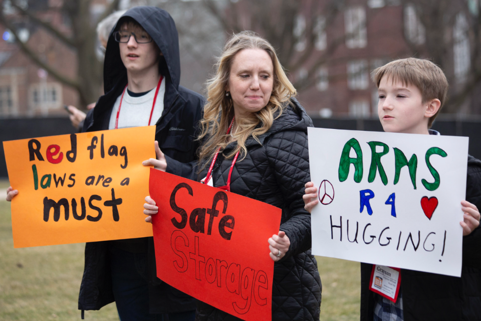 Woman and two youth holding signs at a rally