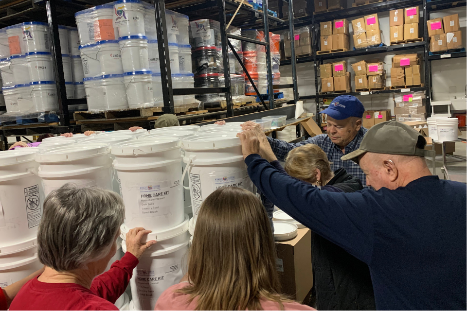 Volunteers praying over a pallet of disaster relief supplies