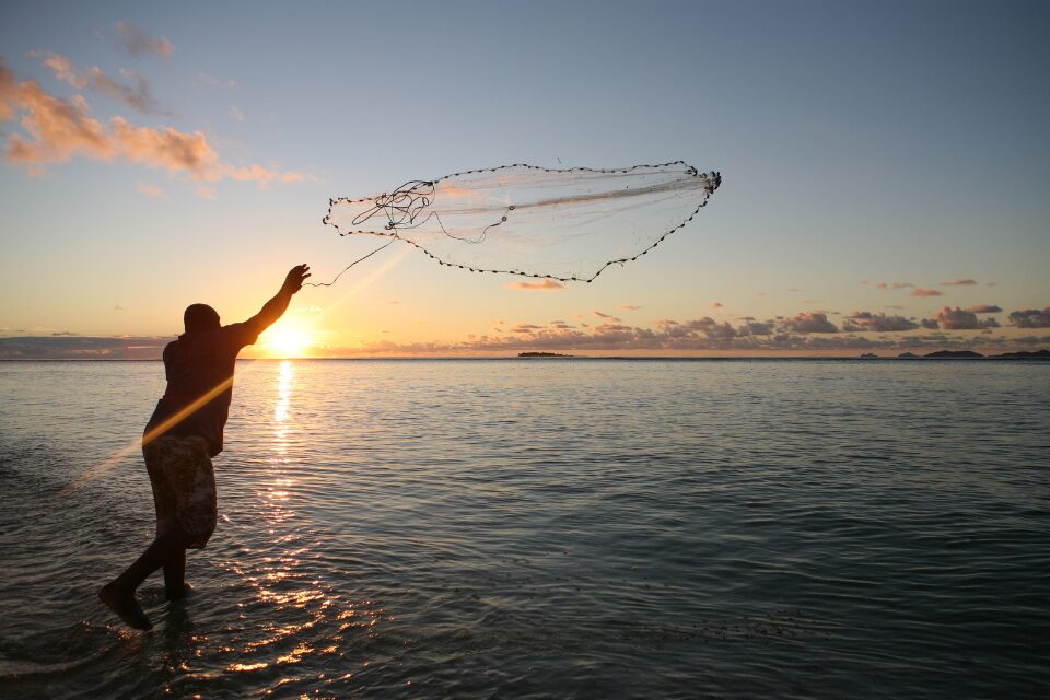 Man casting a fishing net into water