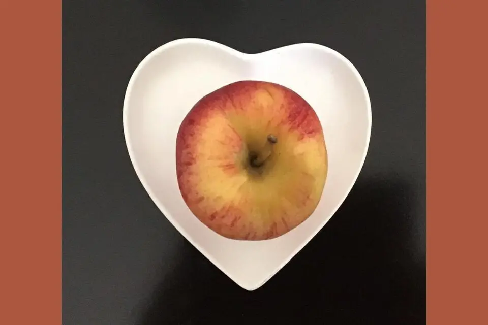 Apple sitting in heart-shaped bowl