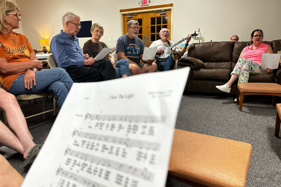 Man playing a banjo and people singing