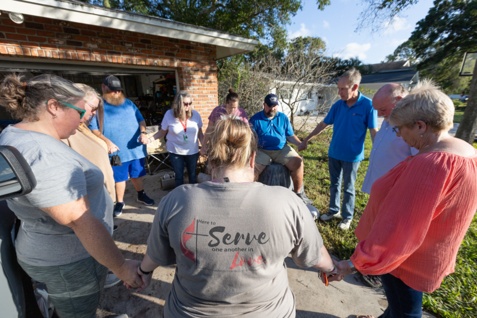 Volunteers pray after hurricane disaster