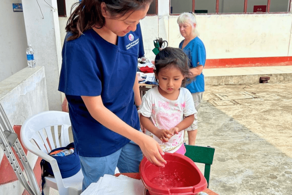 Woman teaching a child how to wash her hands