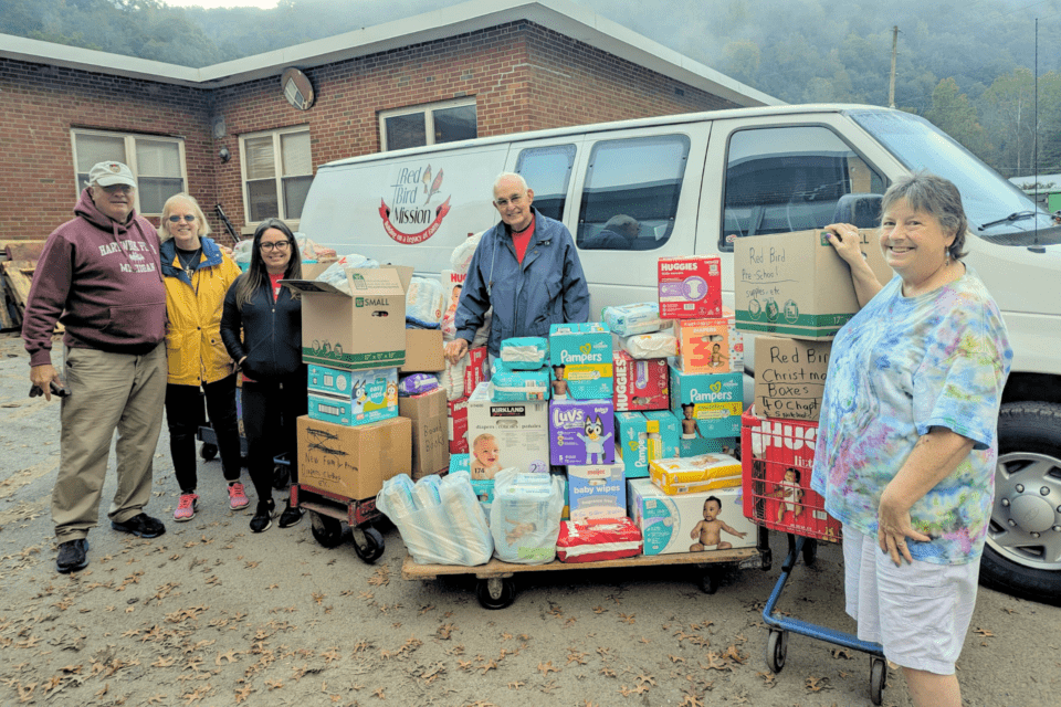 People standing next to cargo van and baby supplies