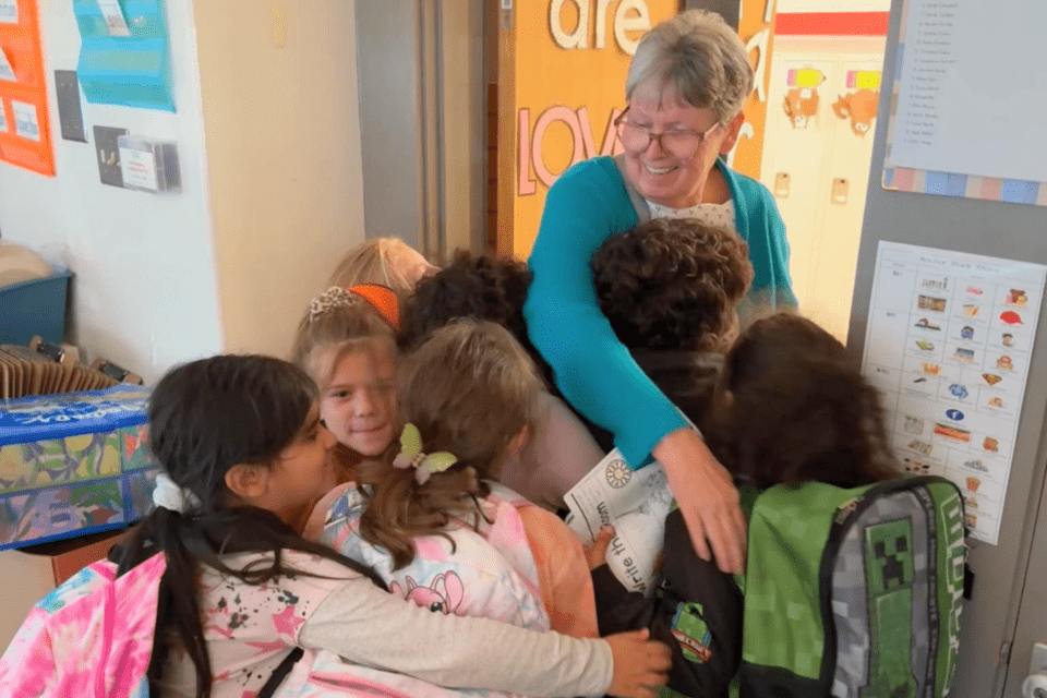 Older adult embracing school children