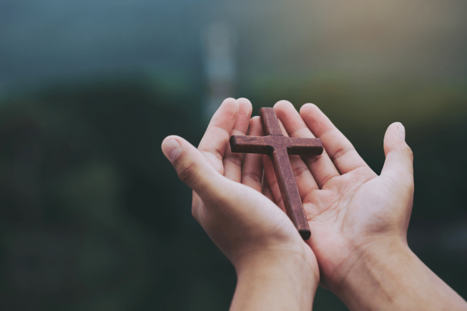 Hands holding a small wooden cross