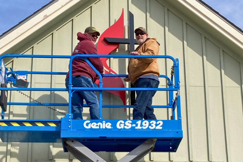Two men hanging a sign on a building