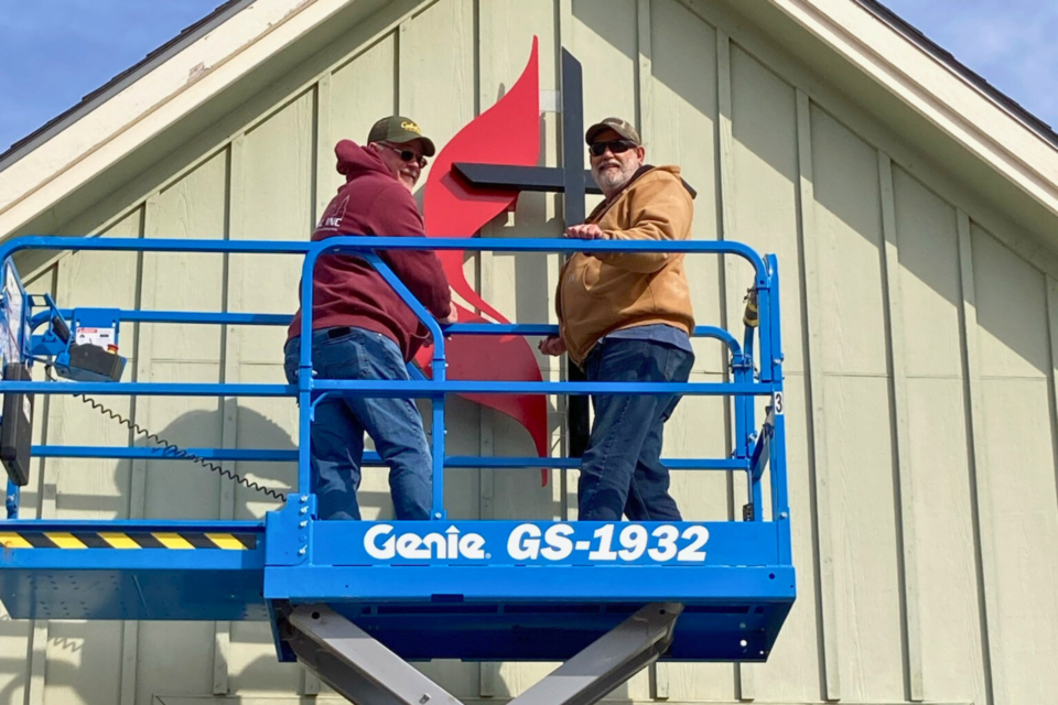 Two men hanging a sign on a building