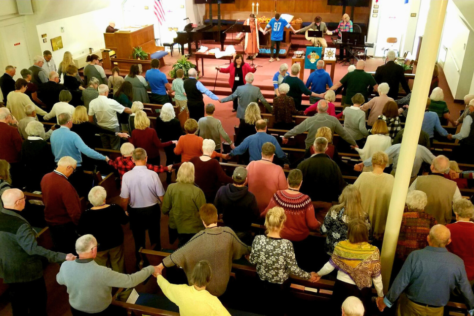 Pastor leading congregation in prayer of blessing
