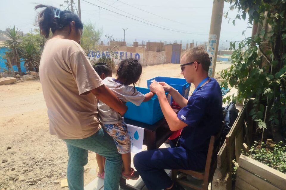 Student showing children how to wash hands