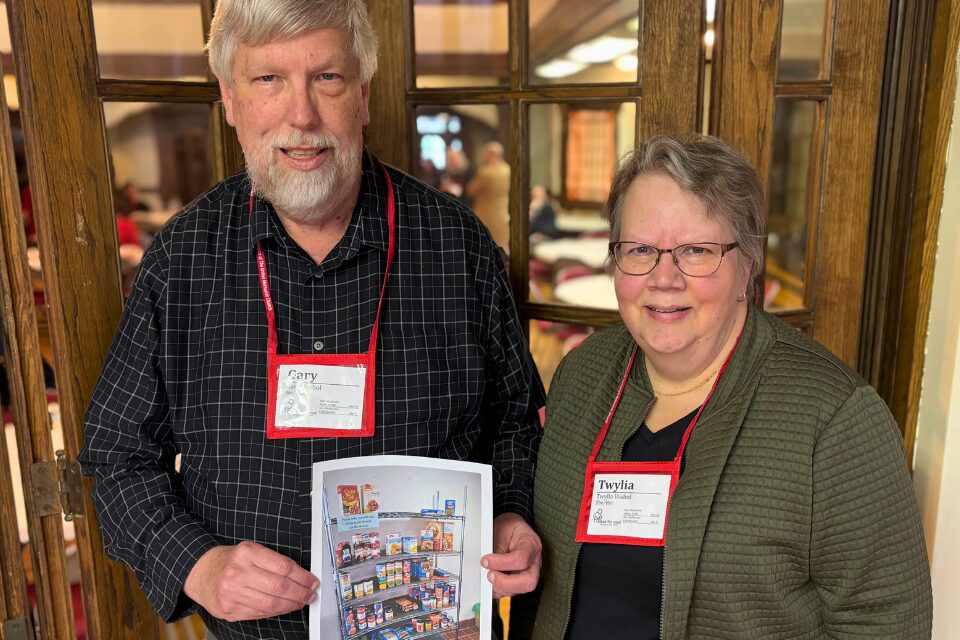 Two church members holding photo of their church's food pantry