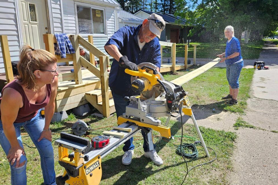 Volunteers cutting lumber to make a ramp
