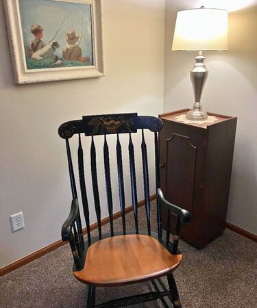Chair in a corner next to a lit lamp