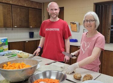Man and woman chopping vegetables for soup