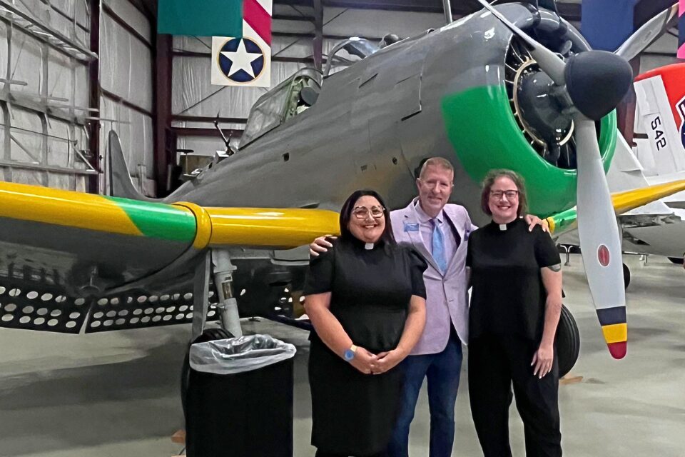 Three people standing in front of an airplane